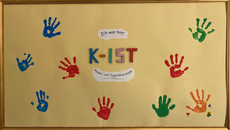 Ein Bild im Rahmen - zu sehen sind mit Farbe aufpresste Kinderhände